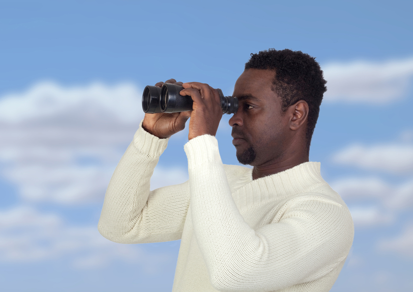 Attractive african man looking through binoculars